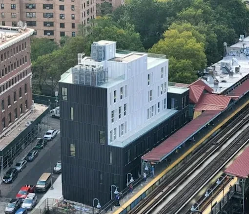 Mid-rise building with rooftop mechanical equipment beside an elevated train line